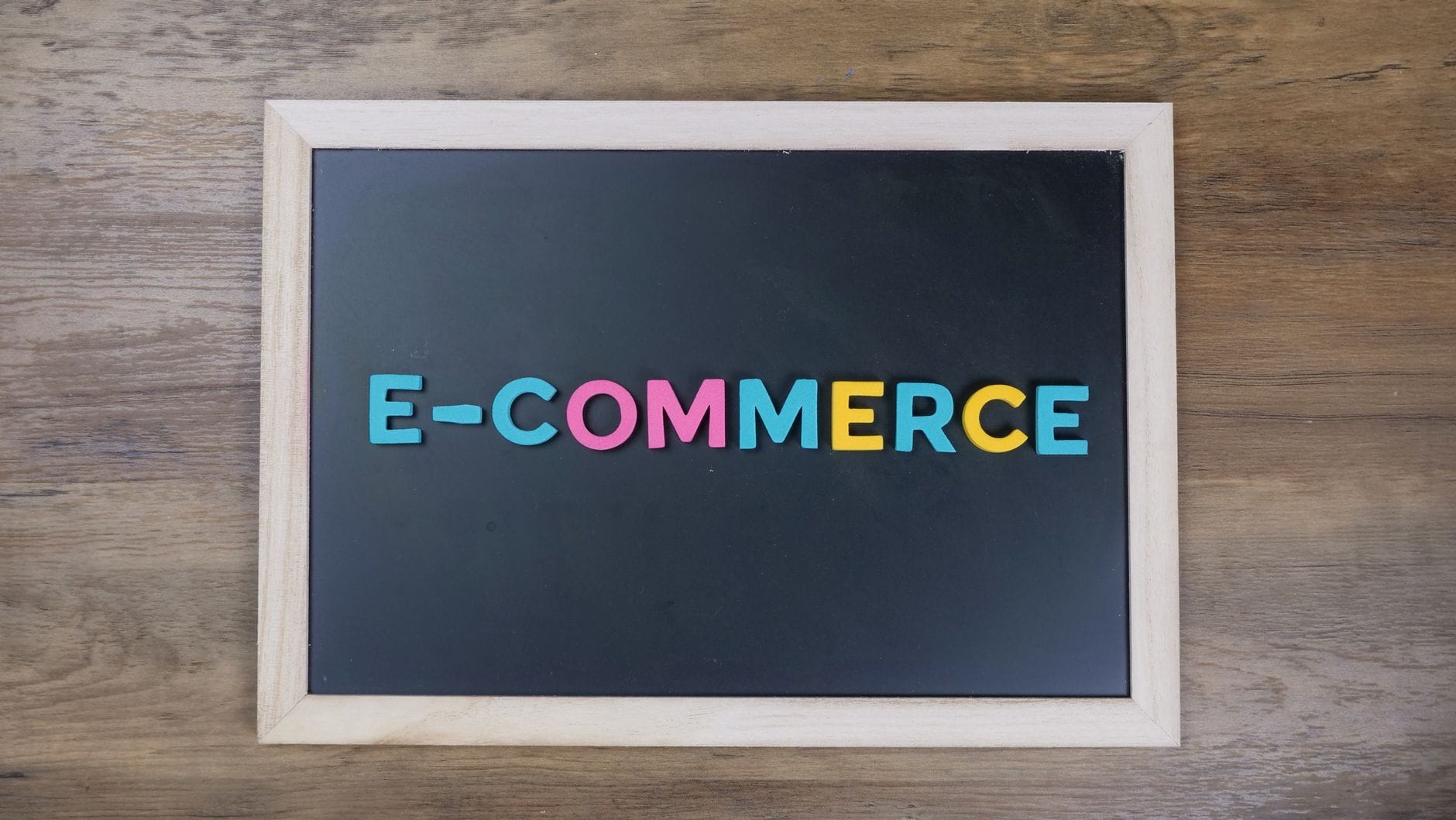 Napisy e-commerce z kolorowych liter na czarnej tablicy z drewnianą ramą
