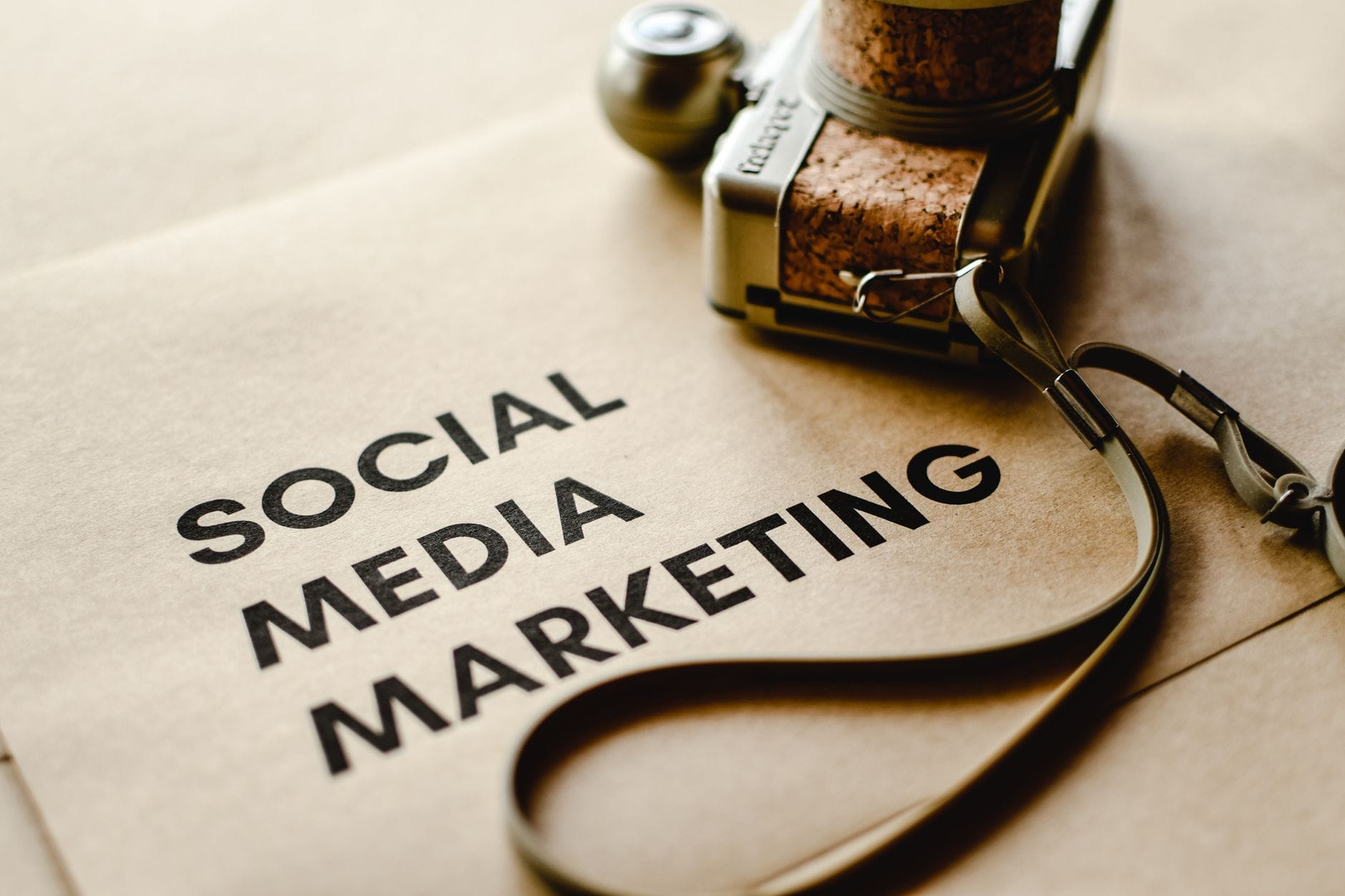 Jak pisać teksty na stronę firmową, które zwiększą widoczność w internecie lokalnych usług Zbliżenie aparatu na papierze z napisem Social Media Marketing