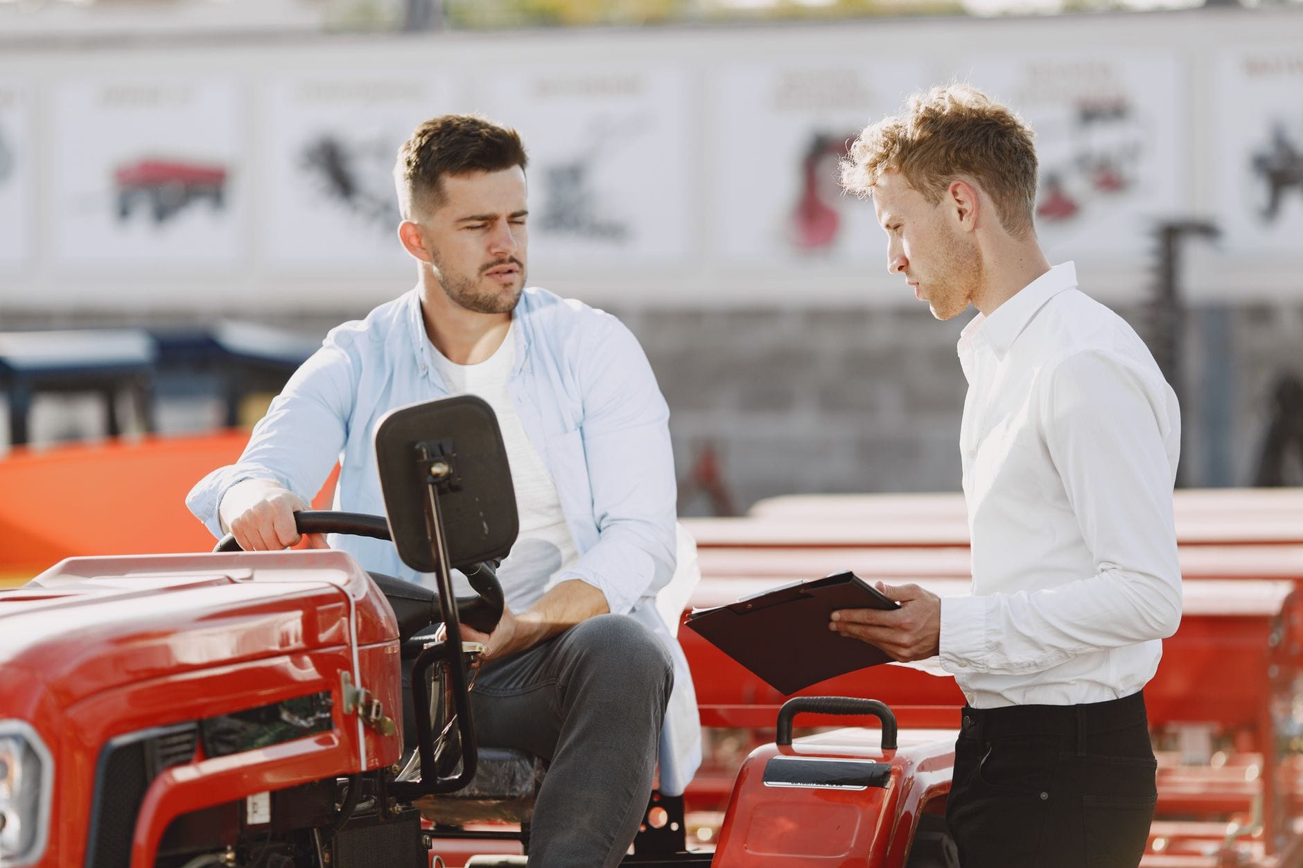 Jak wybrać firmę ogrodniczą: sezonowa usługa czy stała współpraca Dwóch mężczyzn rozmawia o warunkach współpracy przy traktorze